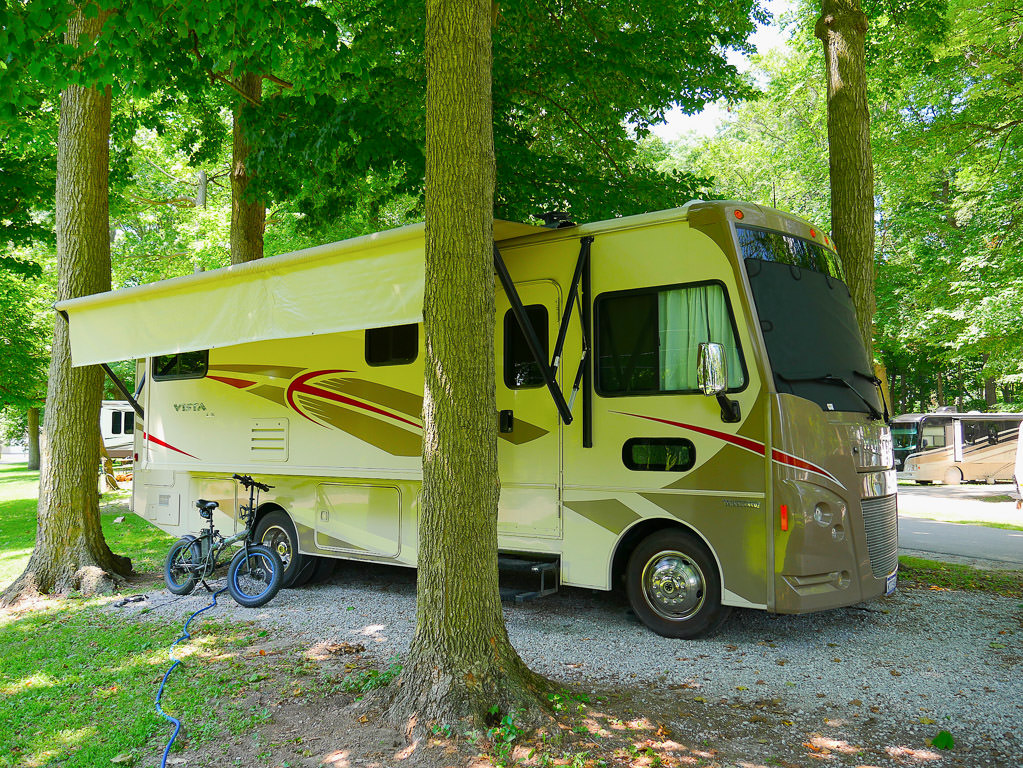 Winnebago Vista in camp with awning deployed and electric bike propped against exterior