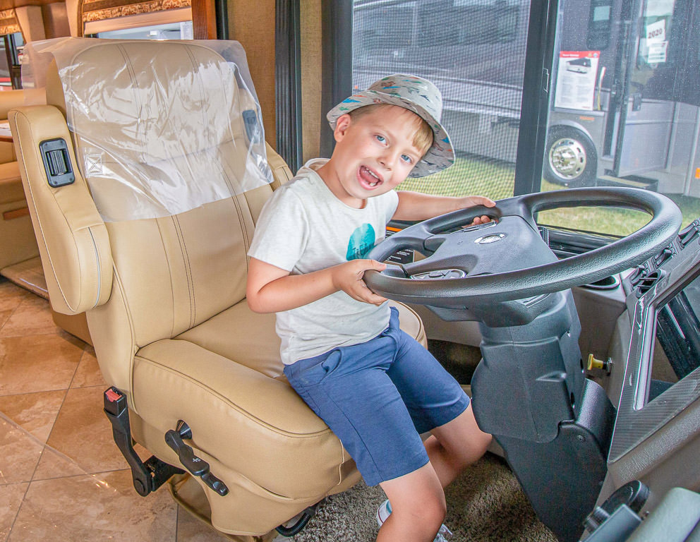 One of the boys in the drivers seat of a display unit in Winnebago product display.