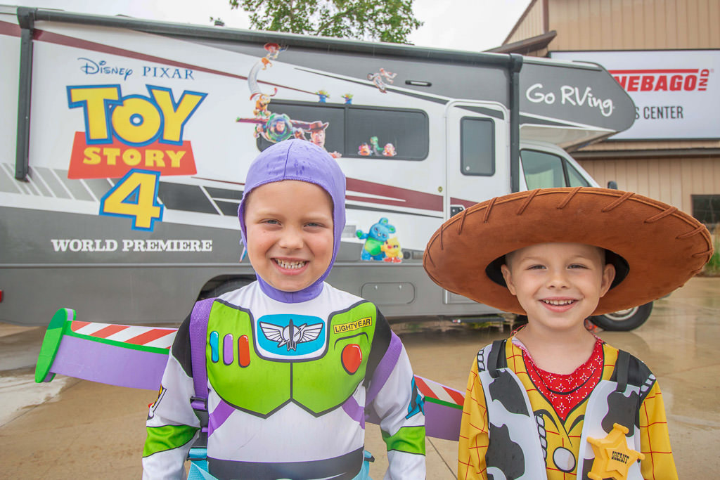 The boys in Buzz Lightyear and Woody costumes in front of the Toy Story 4 unit in front of the Winnebago Visitors Center