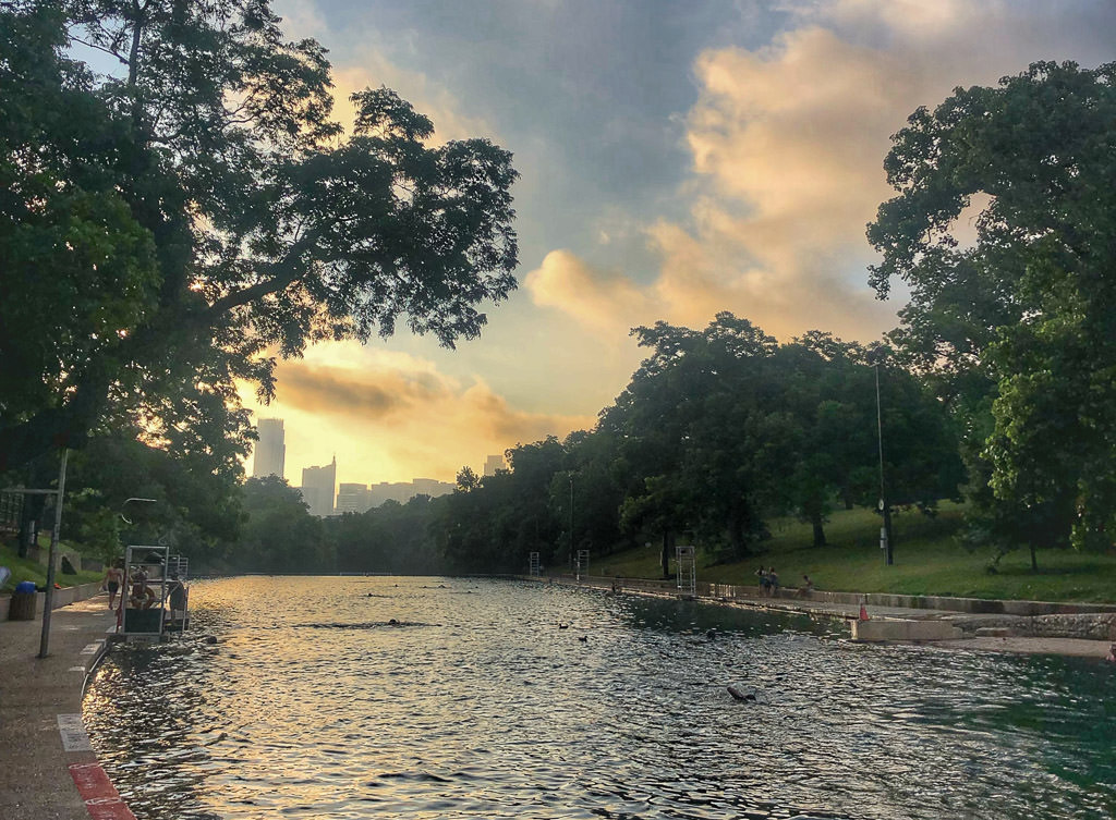 Barton Springs Pool with sun setting in the background.