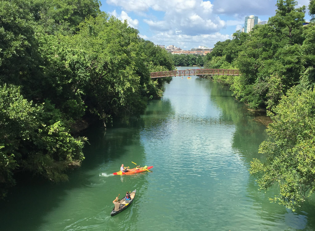 People in kayak and canoe going down Lady Bird Lake.