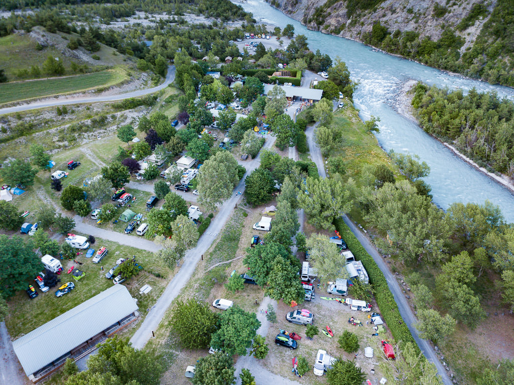 Campground next to river filled with RVs of different types as well as tents.