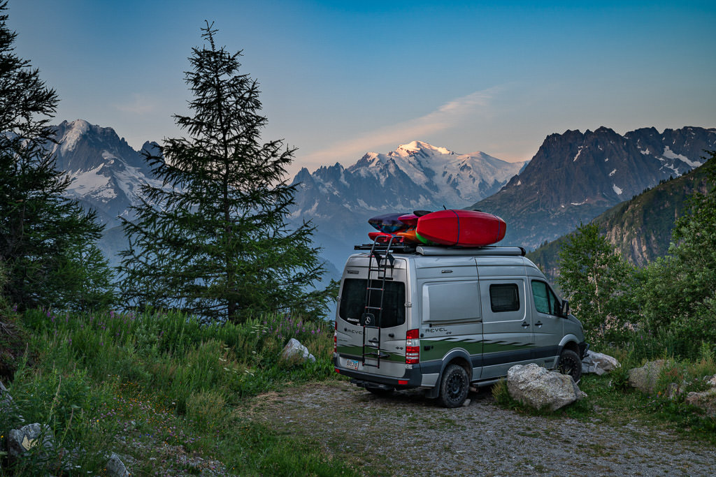 Winnebago Revel parked alone with the snow capped Alps in the background.