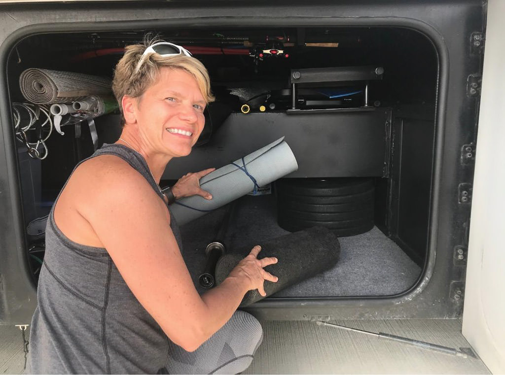 Women pulls gym equipment from exterior compartment storage of her RV